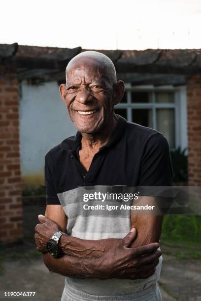 portrait of a smiling retired man in front of his house - old man afro stock pictures, royalty-free photos & images