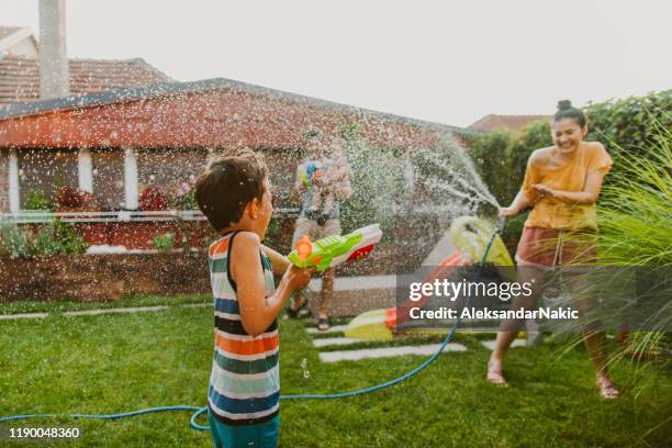 familie water gevecht in de werf - waterpistool stockfoto's en -beelden