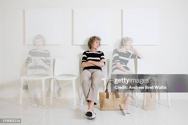 bored senior woman passing time in a waiting room - waiting room stockfoto's en -beelden