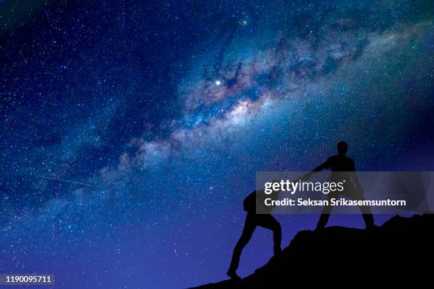 silhouette of giving a helping hand. milky way blackground - cliff texture stock pictures, royalty-free photos & images