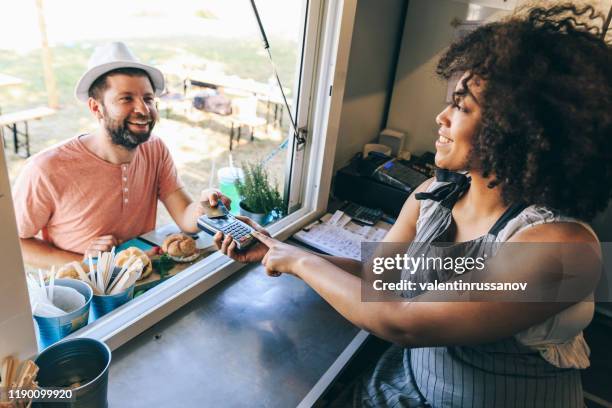 man buying sandwiches from food truck and using credit card - food truck payments stock pictures, royalty-free photos & images