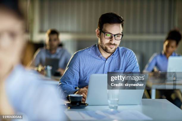 young businessman working on laptop in the office full of people. - corporate learning stock pictures, royalty-free photos & images