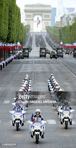 French antiriot police motorcyclists ride their motorbike down the Champs-Elysees with the Arc de Triomphe in the background, during the annual...