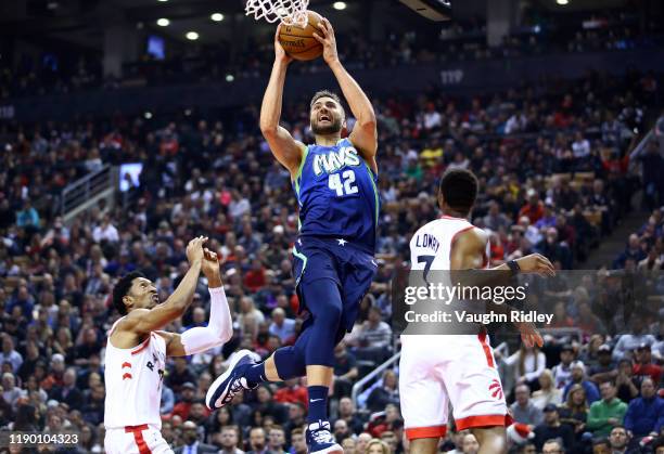 Maxi Kleber of the Dallas Mavericks shoots the ball as Malcolm Miller and Kyle Lowry of the Toronto Raptors defend during the first half of an NBA...