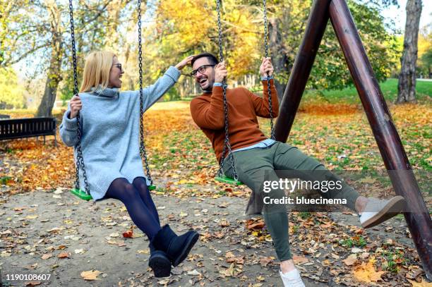 attractive couple in park on swing - woman on swing stock pictures, royalty-free photos & images