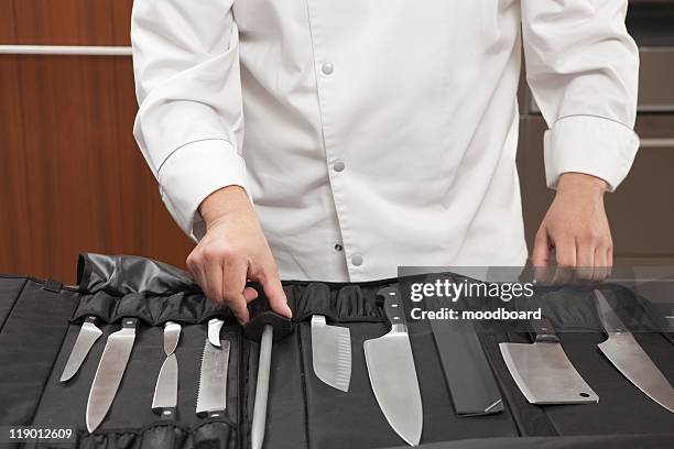mid- adult chef chooses knife - küchenmesser stock-fotos und bilder