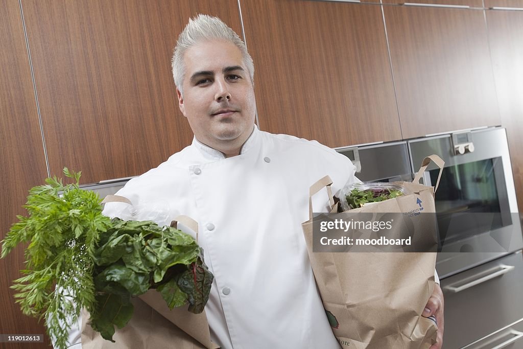 Mid- adult chef with two bags of fresh groceries