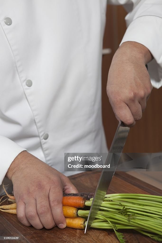 Mid- adult chef cutting carrots