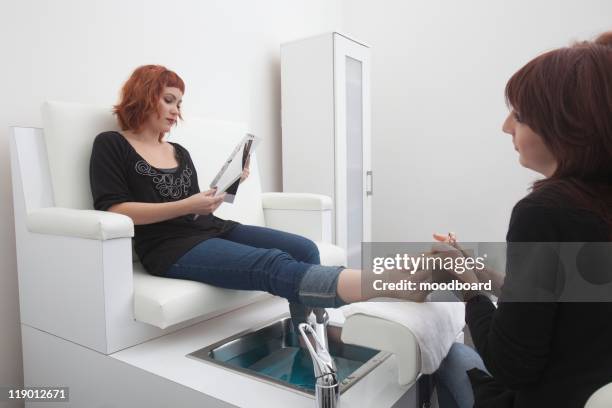 foot masseuse and client in beauty salon - negeren stockfoto's en -beelden