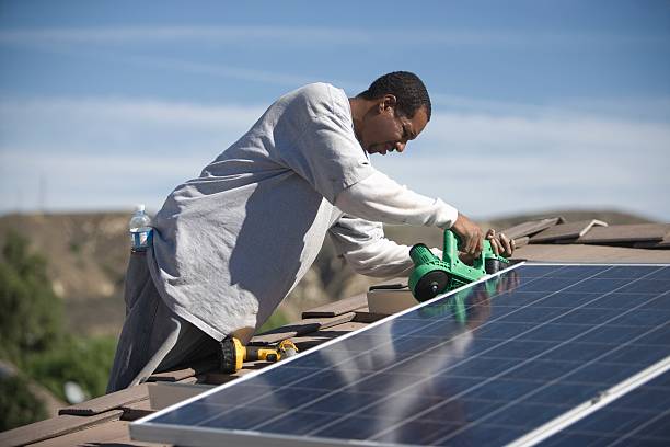 a man on a rooftop working on solar panelling