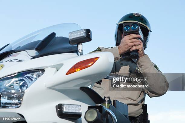 patrol officer sits on motorcycle looking through pseedometer - brigada de trânsito imagens e fotografias de stock
