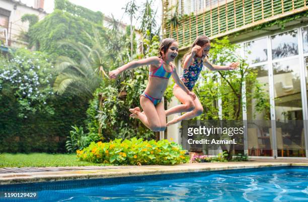 Fun Sisters Jumping into Family Swimming Pool