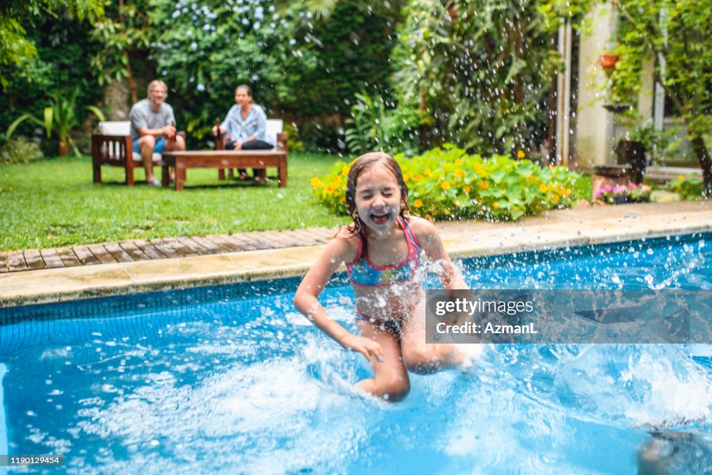 Young Girl Jumping Into Backyard Pool