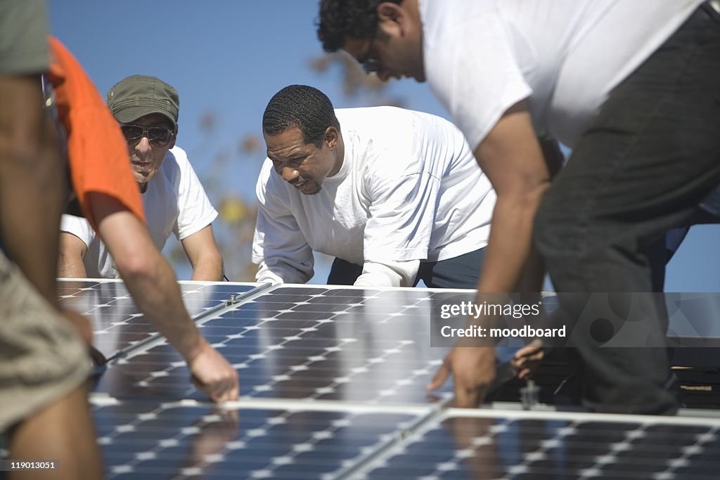 A group of men laying down a large solar panel
