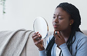 African Girl Looking In Round Mirror and Touching Her Chin