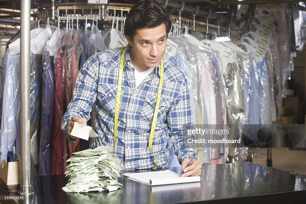 Man working in the laundrette documenting receipts