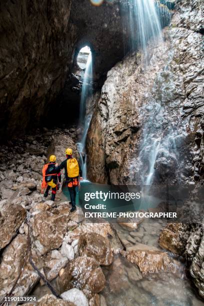 a group of canyoneers marveling a small waterfall in a lagoon-like cave formation - canyoneering stock pictures, royalty-free photos & images