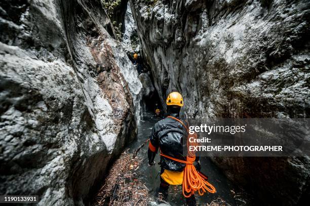 un groupe de canyoneers dans des vêtements en néoprène faisant leur chemin à travers le fond humide et étroit de canyon - résistant à l'eau photos et images de collection