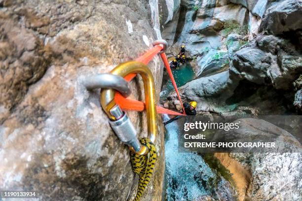 ein abenteurer, der einen kleinen wasserfall hinunterseilt, während er mit seiner gruppe canyoning - bergsteiger gruppe stock-fotos und bilder