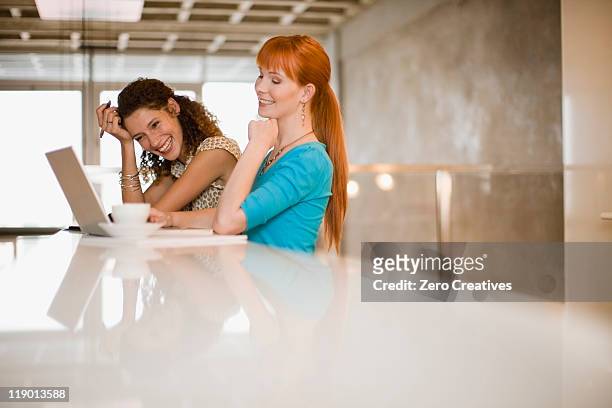mujeres de negocio utilizando una computadora portátil juntos - mesa cafeteria perfil fotografías e imágenes de stock