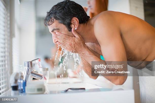 man washing his face in bathroom - rasieren stock-fotos und bilder