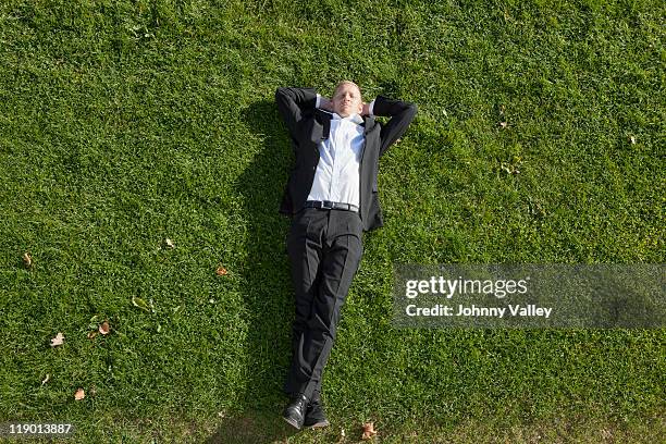 businessman laying in grass - lying down stockfoto's en -beelden