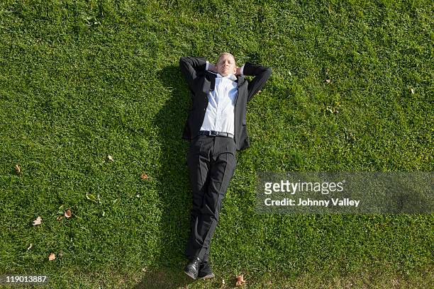 businessman laying in grass - lying down stock pictures, royalty-free photos & images