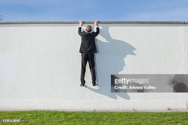 businessman climbing en pared - barrier fotografías e imágenes de stock