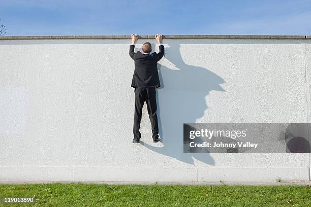 businessman climbing over wall - boundary stock pictures, royalty-free photos & images