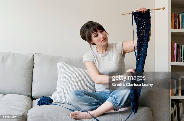 woman examining knitting in living room - masche stock-fotos und bilder