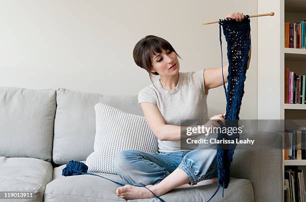 woman examining knitting in living room - aiguille à tricoter photos et images de collection