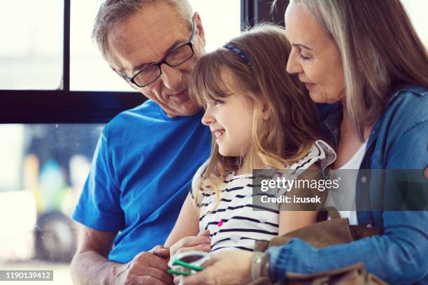 glückliches mädchen pendelt mit großeltern im bus - kids sitting together in bus stock-fotos und bilder