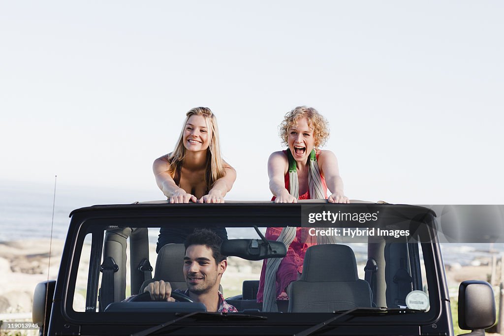 Women standing in jeep on road trip