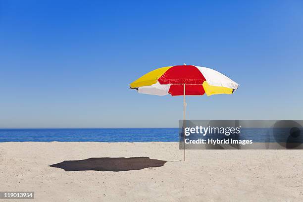 umbrella in sand on empty beach - parasols stockfoto's en -beelden