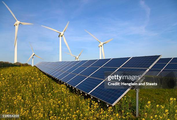 solar panels and wind turbines in field - zonnecellen stockfoto's en -beelden