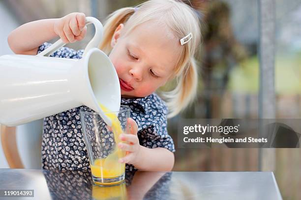 toddler girl pouring glass of juice - orangensaft stock-fotos und bilder