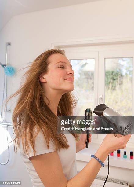 teenage girl blow drying her hair - haare föhnen stock-fotos und bilder