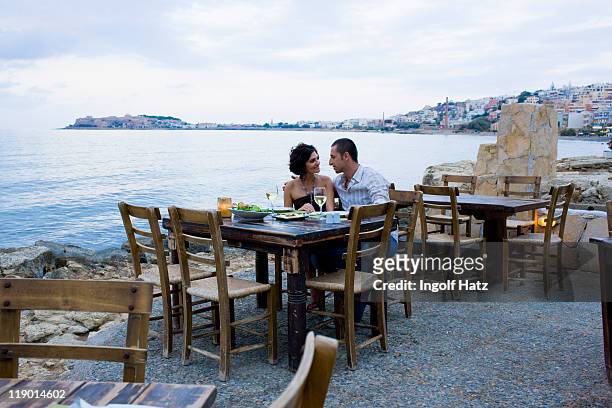 couple eating at waterfront cafe - greece stock pictures, royalty-free photos & images