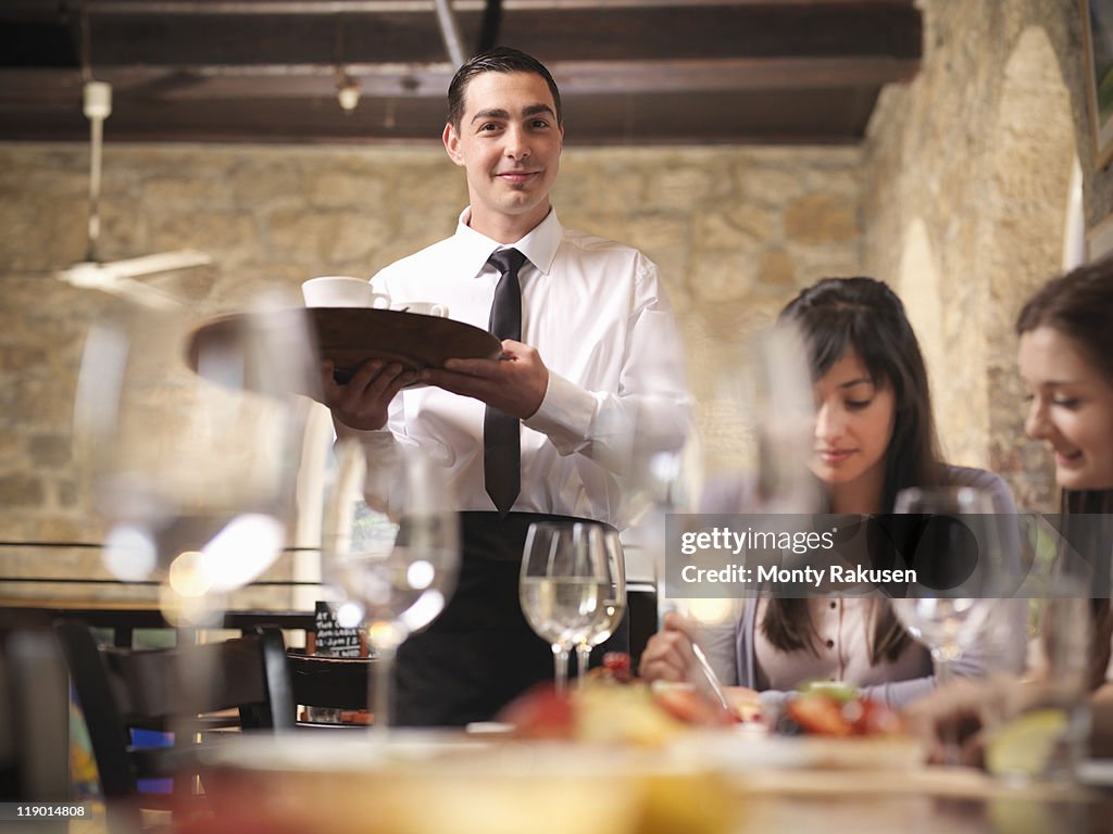 Waiter serving people in restaurant