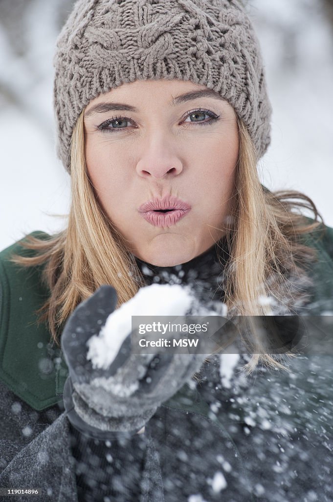 Woman blowing handful of snow