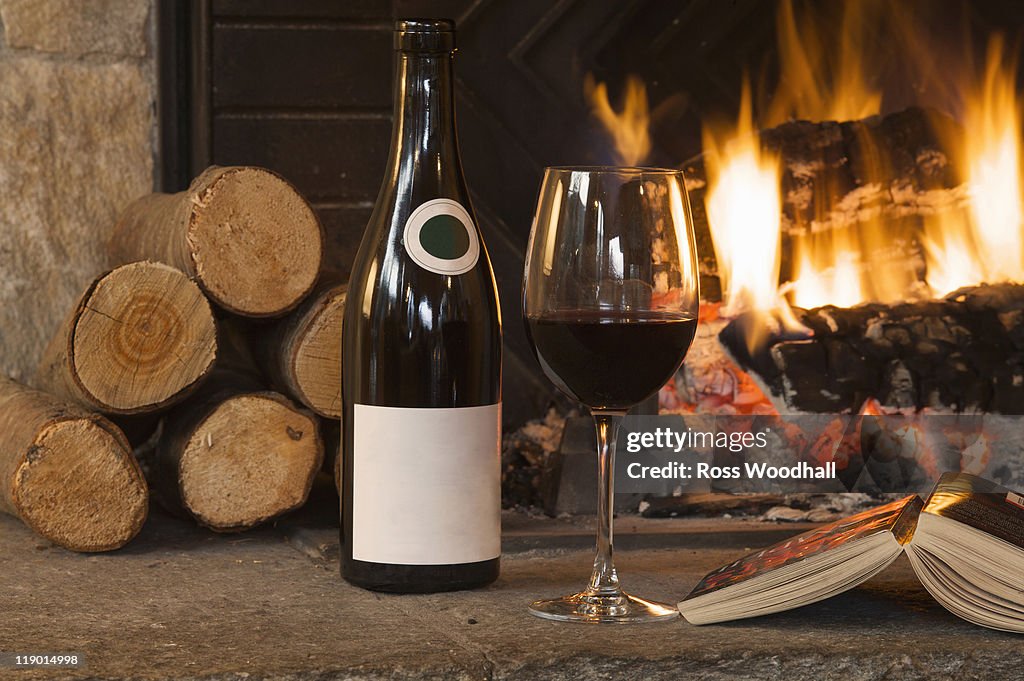 Glass of wine and book by fireplace