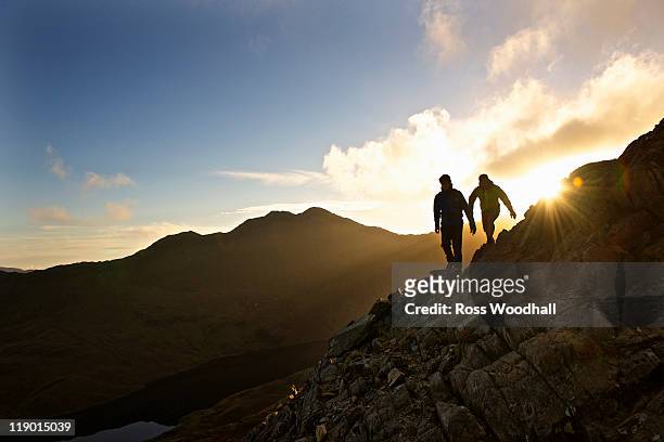 men hiking on rocky mountainside - welsh hills stock pictures, royalty-free photos & images