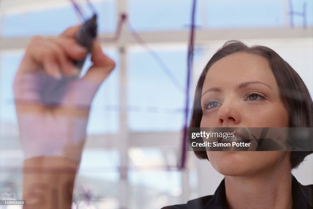 Businesswoman drawing graph on glass