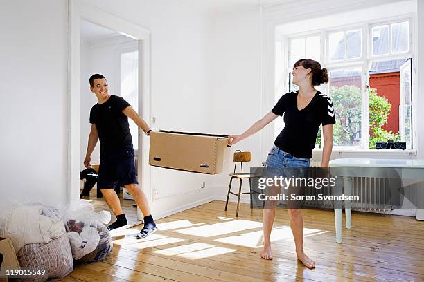 couple carrying box in new home - to pull together stock pictures, royalty-free photos & images