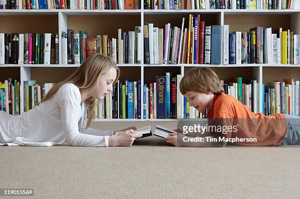 children reading by bookshelves - 10 11 jaar stockfoto's en -beelden