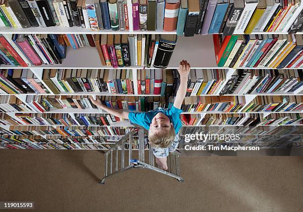 boy using stepladder on bookshelves - child reaching stock pictures, royalty-free photos & images