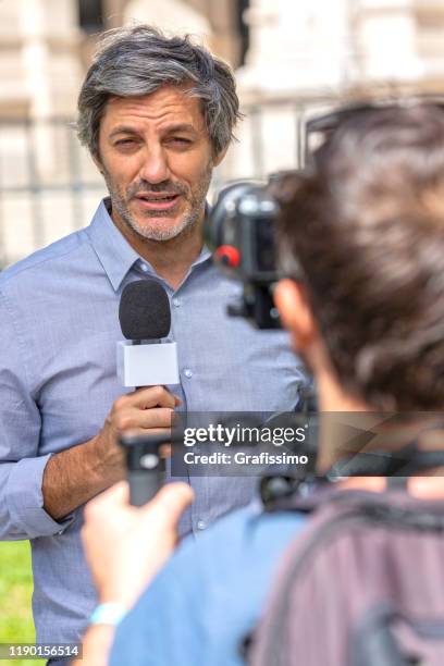 tv-reporter mit mikrofon überträgt für die nachrichten live - fernsehreporter stock-fotos und bilder