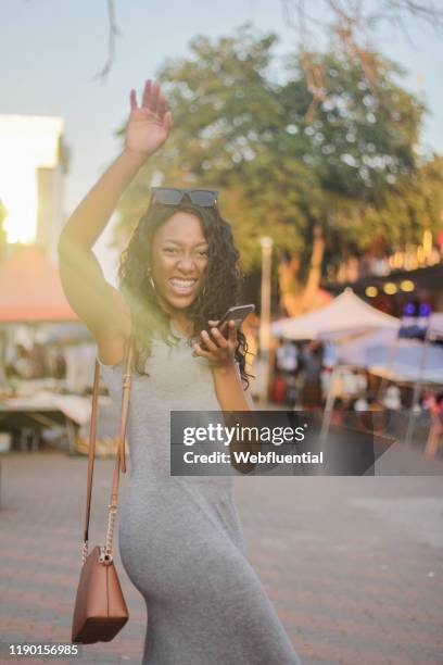 african girl standing in a market holding a smartphone - webfluential bildbanksfoton och bilder