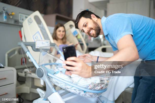 happy father taking a selfie of his newborn and wife in the hospital - baby care stock pictures, royalty-free photos & images