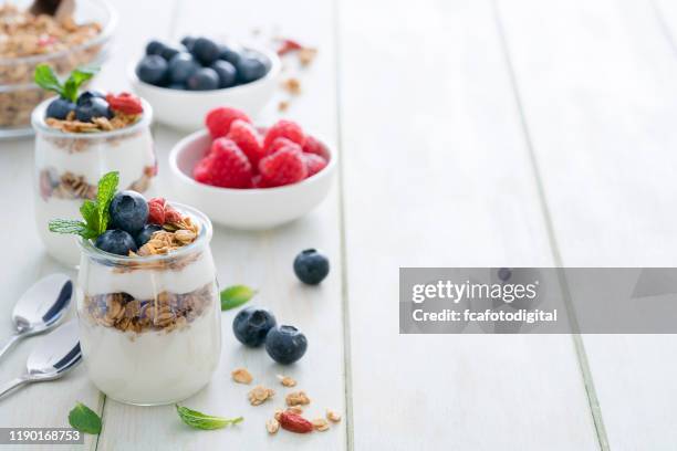 healthy food: homemade yogurt with granola on breakfast table. copy space - greek yogurt stock pictures, royalty-free photos & images